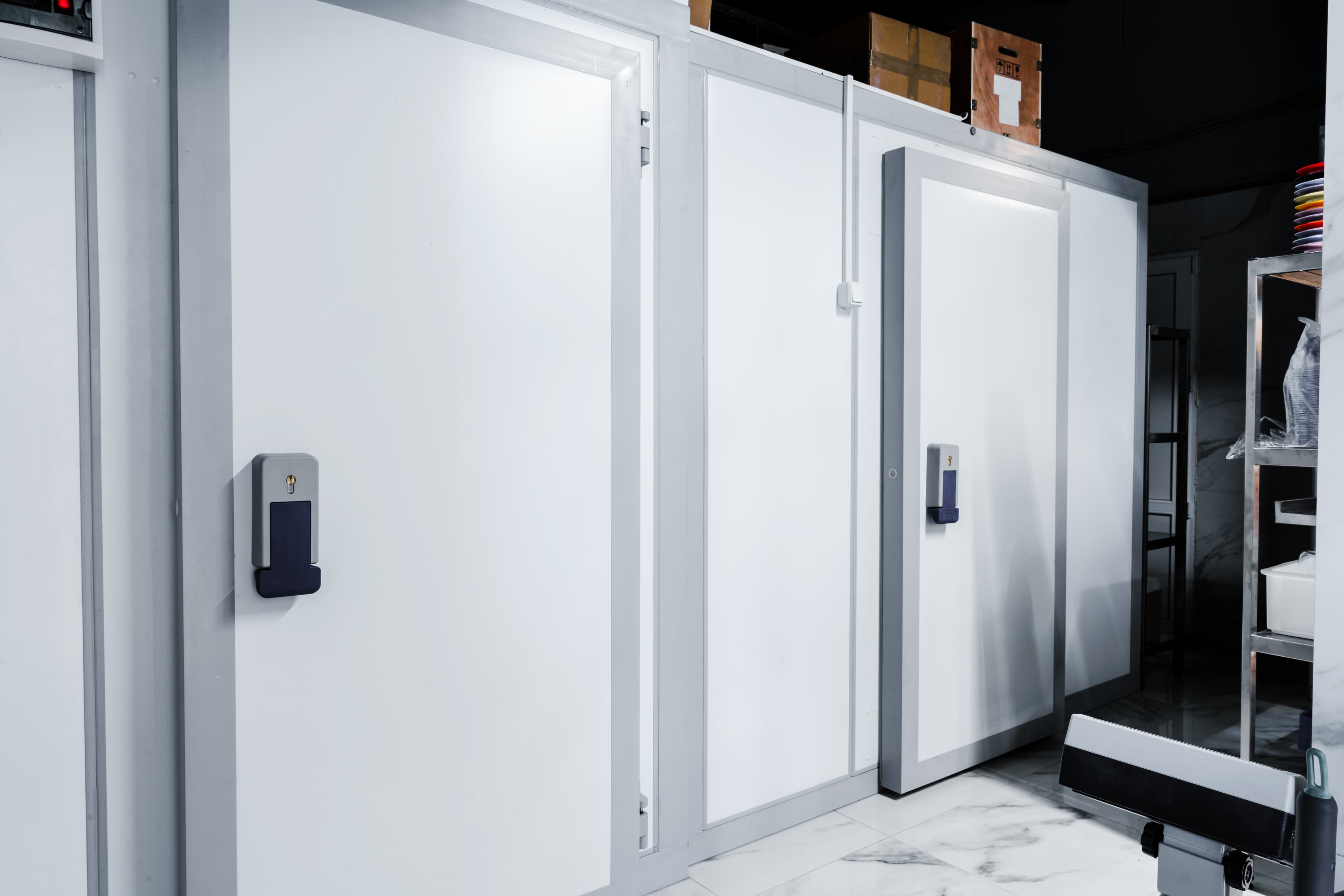 Row of white industrial doors with electronic keypads showing control interfaces for monitoring systems
