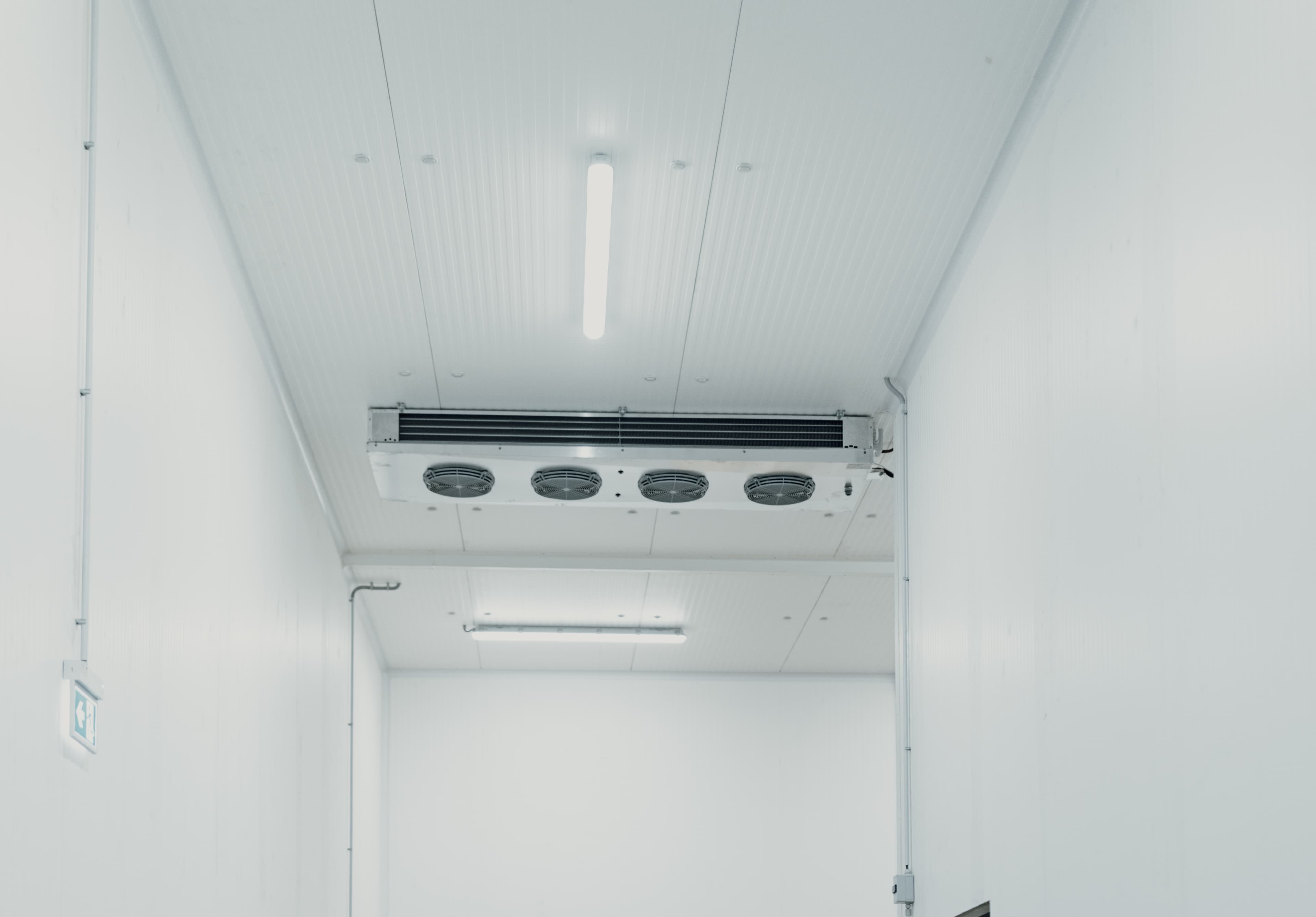 Industrial refrigeration unit mounted on white ceiling in a clean, minimalistic environment